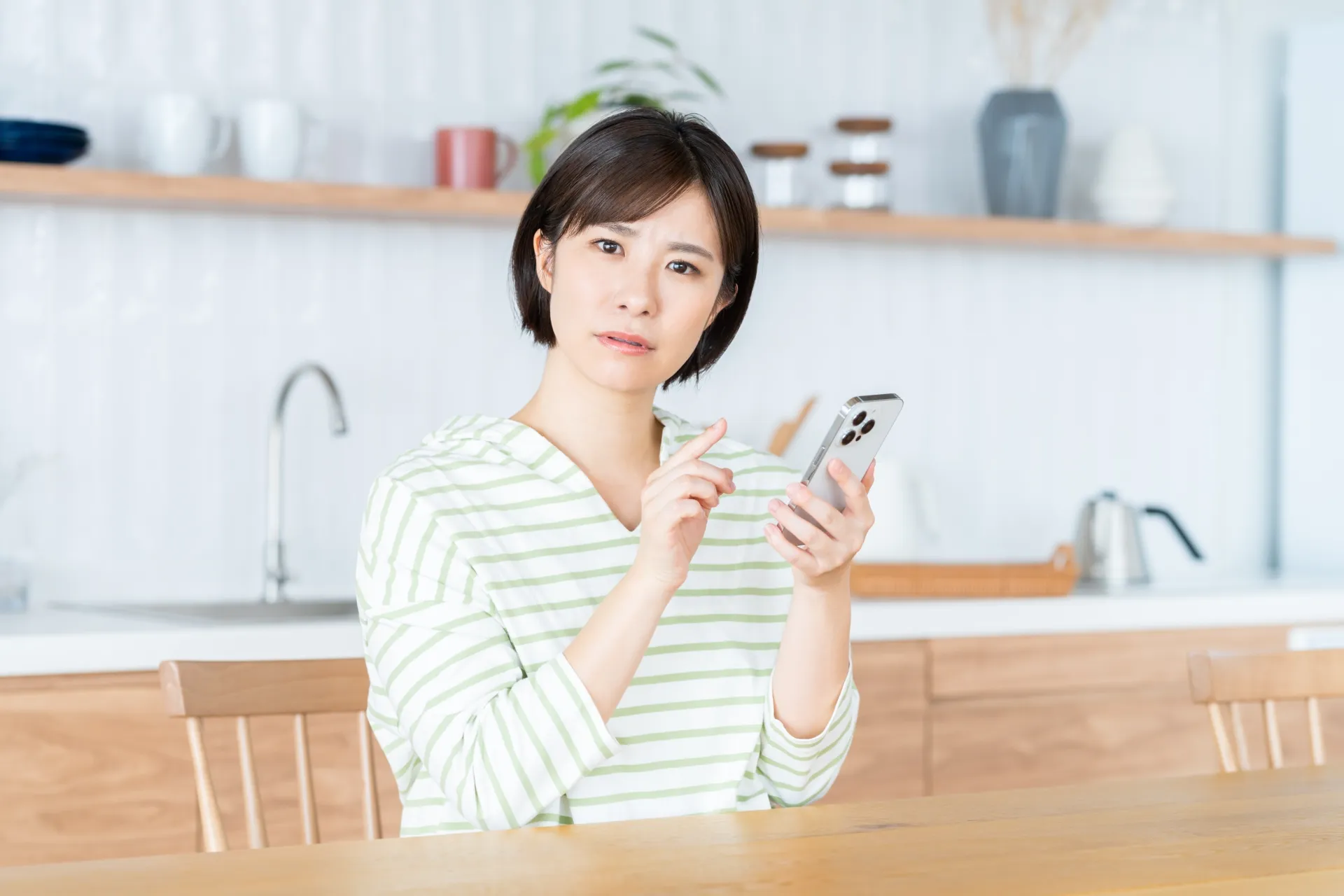 スマートフォンを見て考え込む女性